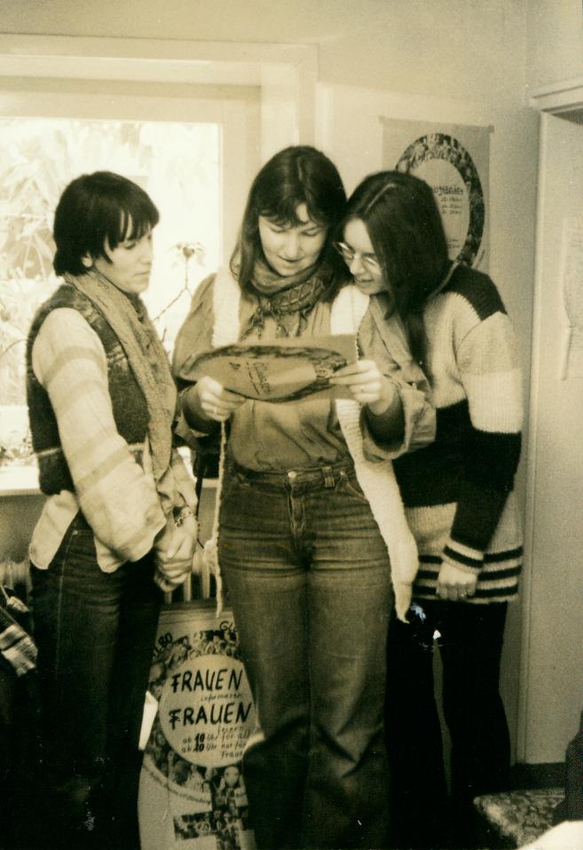 Auf dem Bild sind drei Mitarbeiterinnen der Frauenberatung zu sehen, das Foto entstand vermutlich Ende der 1970er Jahre. Sie sind über ein Bild gebeugt, welches sie gemeinsam anschauen.